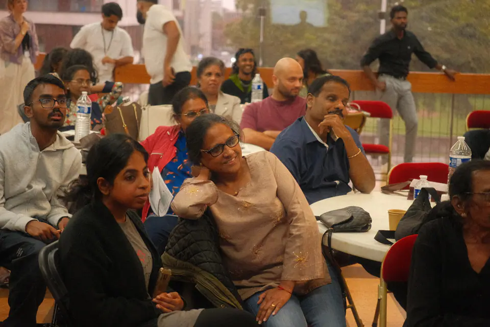 Participants of all ages listen closely to a talk, seated around tables