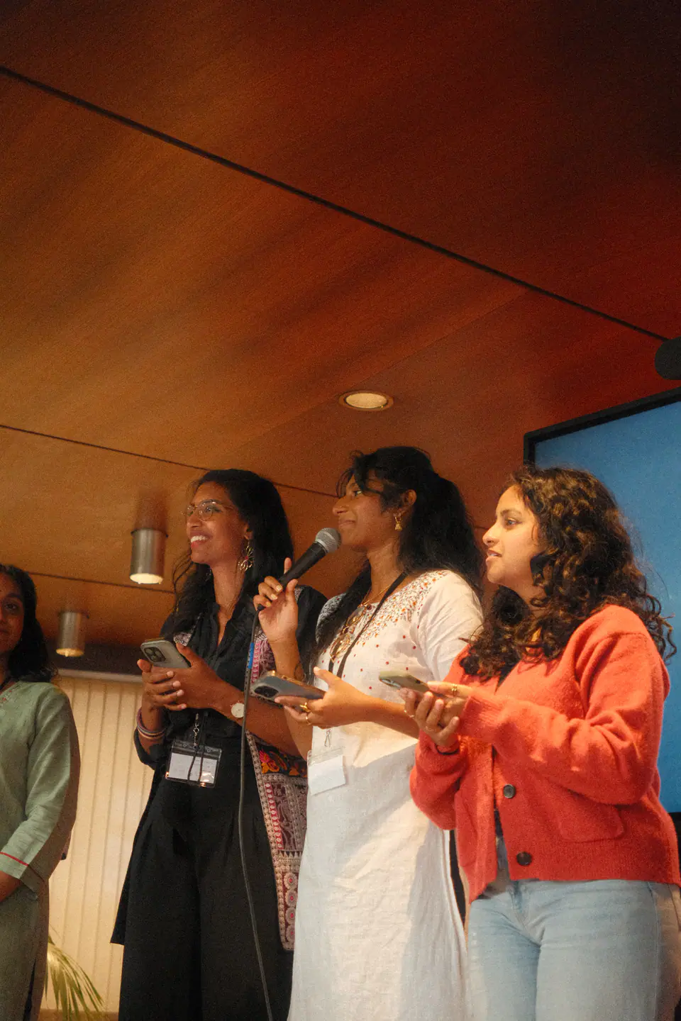 Three smiling team members address the audience with a microphone